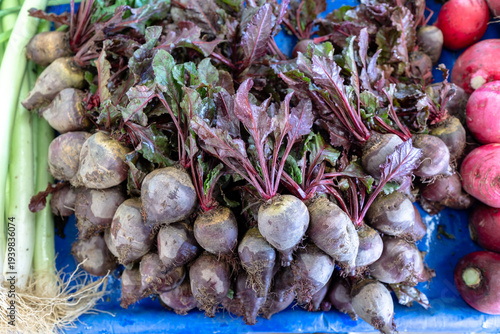 Fresh organic red beets with green leaves on a blue market stall