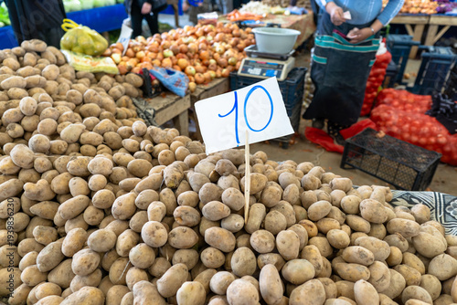 Large pile of fresh potatoes with price tag at a traditional farmer's market