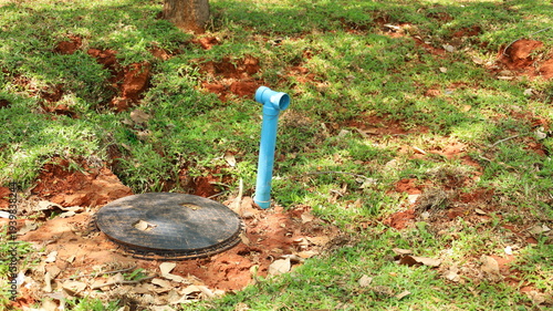 Septic tank with ventilation pipe. Black septic tank buried in the ground with blue ventilation pipe of toilet sanitation system with selective focus.