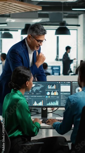 Team members work together in an office to analyze data and prepare reports while using computers and charts in a modern workspace