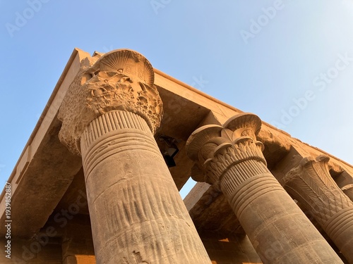 ASWAN, EGYPT - NOVEMBER 7, 2025: Side view of Philae Temple ruins with ancient Egyptian columns and carvings on Agilkia Island near Aswan Egypt under bright blue sky