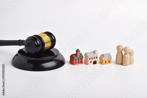 Judge gavel with miniature houses and wooden family figures on white background.