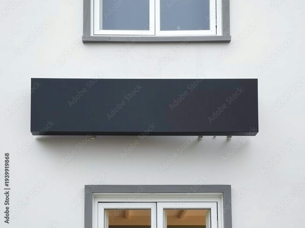 Fototapeta premium A black object mounted on a wall between two windows