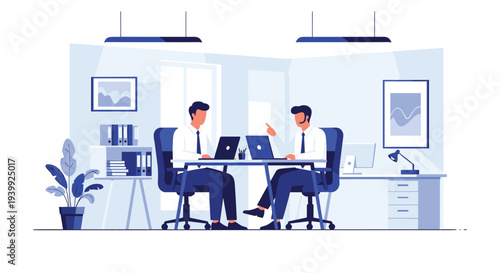 Pair of male colleagues sitting at a shared desk in a modern office environment working on laptops and engaged in a professional talk.
