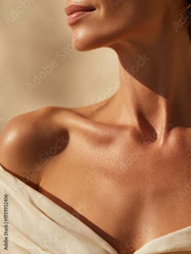 Skincare and beauty branding – close-up of woman neck and collarbone with sun-kissed glowing skin, minimal warm background