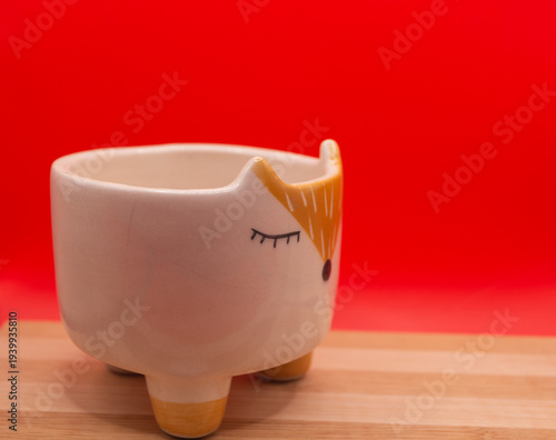 Subject shot of funny ceramic pot made as funny cartoon fox. Bright plant pot for interior design is isolated on the white background.