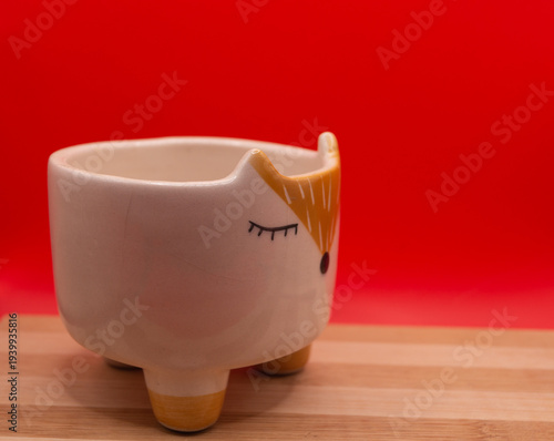 Subject shot of funny ceramic pot made as funny cartoon fox. Bright plant pot for interior design is isolated on the white background.