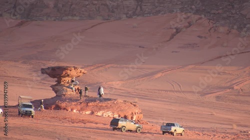 Tourists visiting mushroom rock in Wadi rum with off road vehicles red sand tracks desert landmark adventure travel Jordan