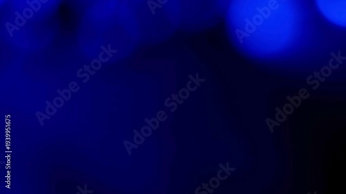 Blue light leaks create a soft abstract texture with glowing circular bokeh effects on a dark background.