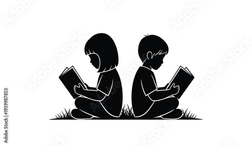 Two children sitting on grass reading books together in silhouette