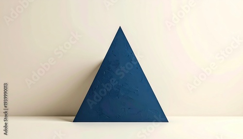 Blue geometric triangle leans on white wall, with soft lighting and minimalist backdrop, for design use
