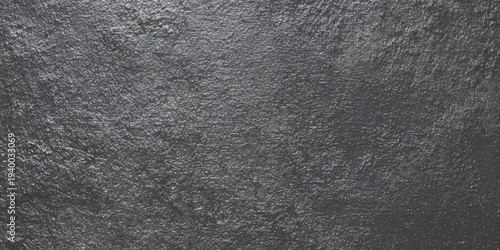 A detailed close up view of a heavily textured dark gray stone surface showcasing natural variations and rough patterns