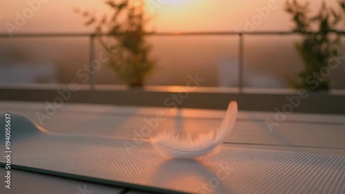 White feather suspended over a yoga mat during golden hour