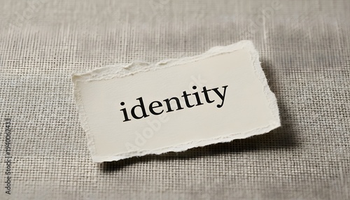 A torn paper fragment displaying the word identity set on a textured background, exploring self-awareness concept