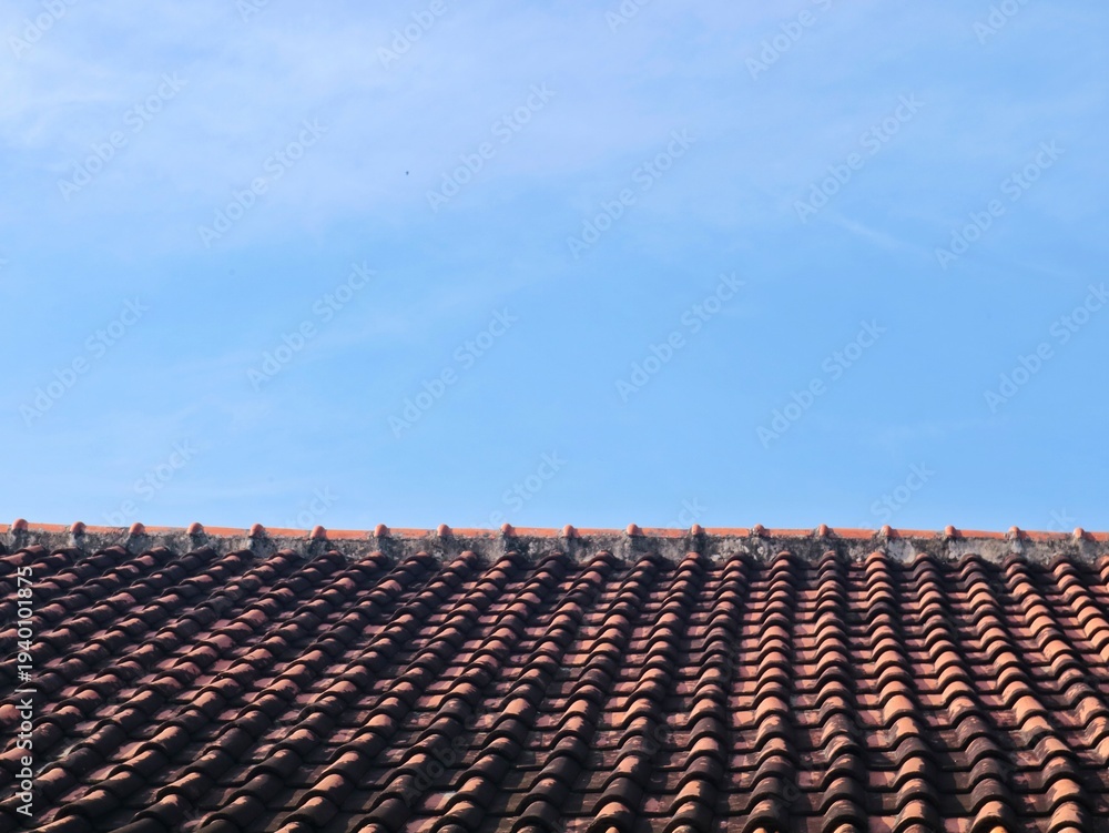 Fototapeta premium Traditional mediterranean terracotta roof tiles under a clear blue sky. Perfect for construction, real estate, or travel-themed projects