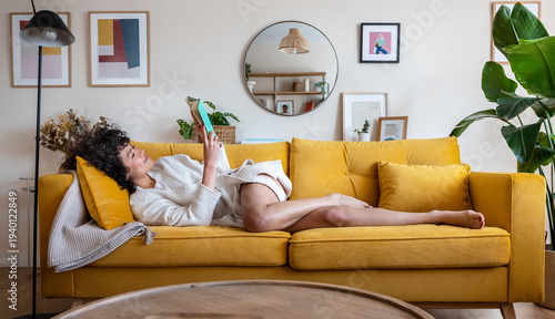Photos Woman relaxing on yellow sofa reading book