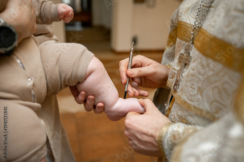 Quadro em tela Orthodox priest anointing newborn baby foot with holy oil during baptism ceremon