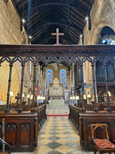 Fényképezés The chancel of St Mary de Castro Church in Leicester, England, features an ornate wooden rood screen framing the view toward the altar and stained glass windows
