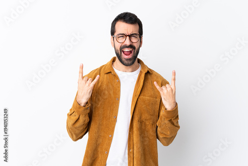Caucasian handsome man with beard wearing a corduroy jacket over isolated white background making rock gesture