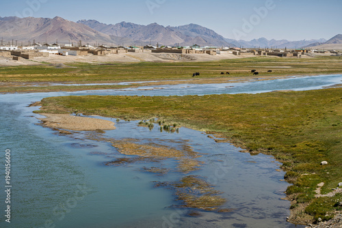 Scenic high-altitude mountain landscape view of Alichur river and village with grazing yaks, Murghab, Gorno-Badakhshan, Tajikistan Pamir