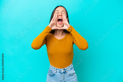 Young caucasian woman isolated on blue background shouting to the front with mouth wide open