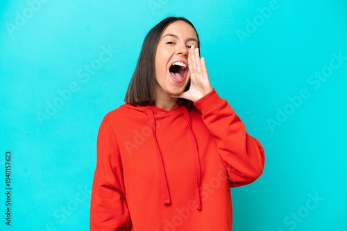Young caucasian woman isolated on blue background shouting with mouth wide open to the side
