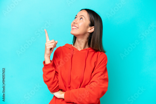 Young caucasian woman isolated on blue background pointing up a great idea