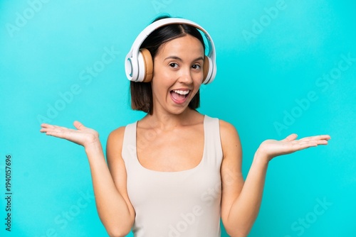 Young caucasian woman isolated on blue background surprised and listening music