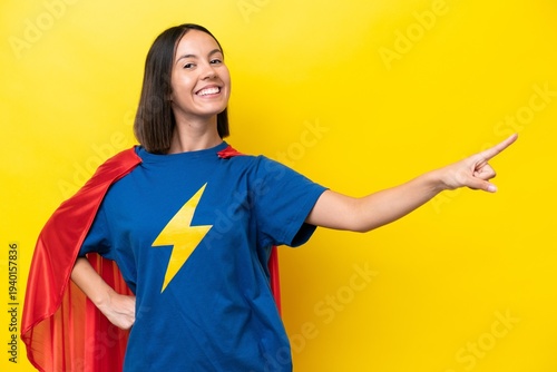 Young caucasian woman isolated on yellow background in superhero costume with proud gesture