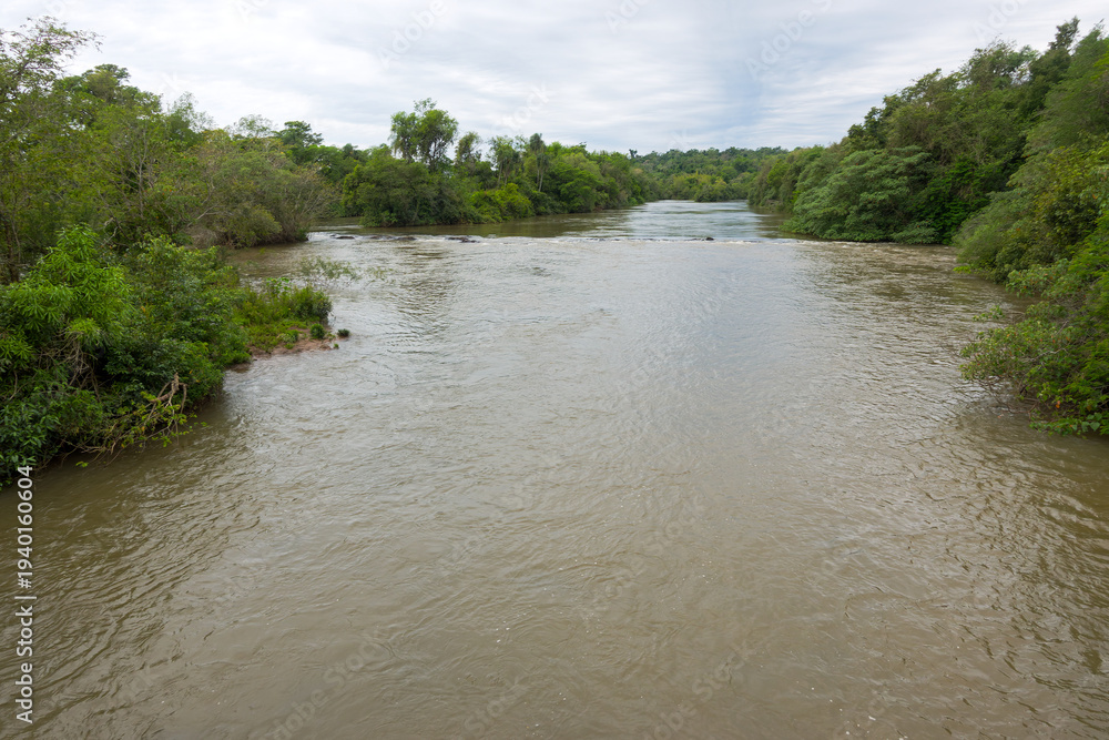 Fototapeta premium Scenic landscape with Iguazu River at Iguazu National Park with famous Iguazu Falls on a cloudy spring day. Photo taken October 7th, 2025, Iguazu National Park, Argentina.
