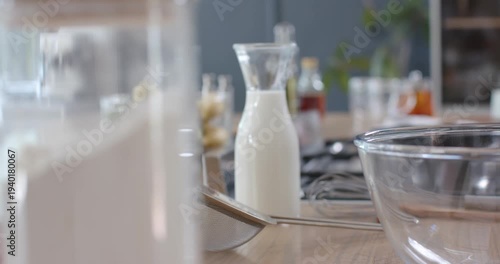 Camera pulling back while racking focus, milk carafe centering and whisk moving forward for baking