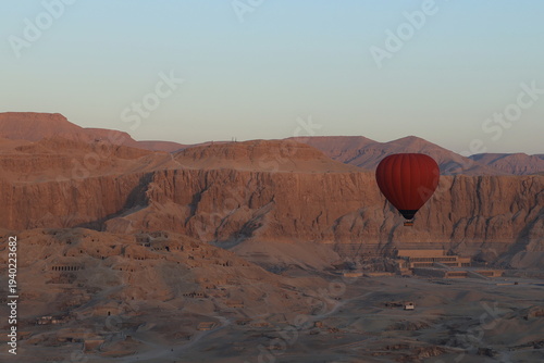 Red Hot Air Balloon Flying at Sunrise in over Mortuary Temples (West Bank, Luxor, Egypt)
