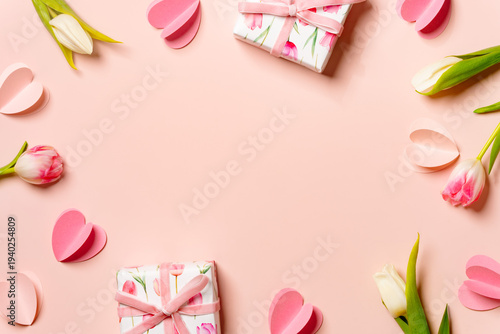 Spring background with tulips, gift boxes and petals for Mother’s Day and Women’s Day on soft pastel backdrop.