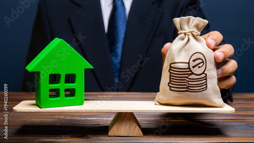 Green house and money bag balanced on wooden scale