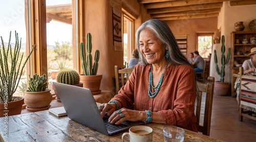 Senior Indigenous Woman Working on Laptop in Sunlit Desert Adobe Cafe