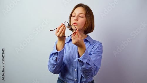 Young girl holding glasses for vision checking quality thoughtful girl examining eyeglasses careful inspection purchase decision selecting new frames choosing optics studio portrait 