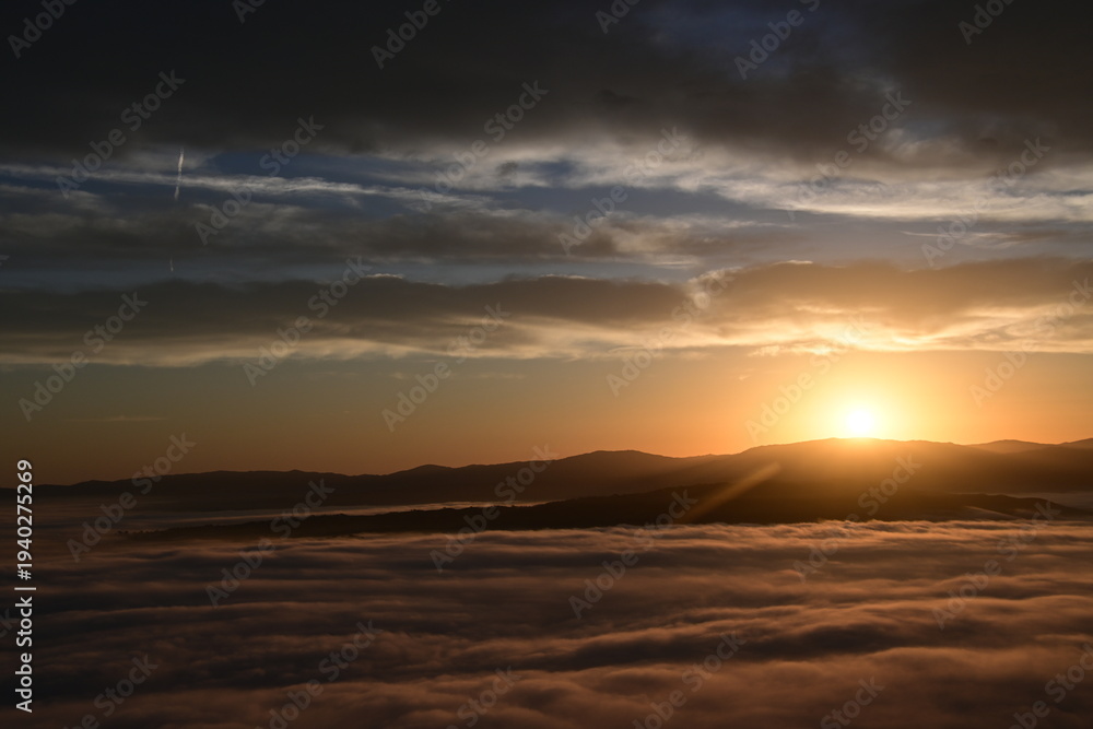 Fototapeta premium cloudy sunrise above the fog and below the clouds