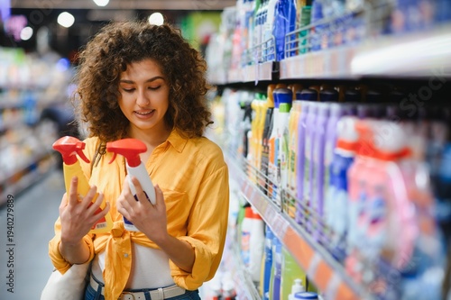 Obraz na płótnie Woman comparing cleaning products in supermarket aisle