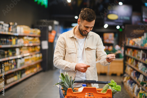 Man smiling while checking grocery list in supermarket