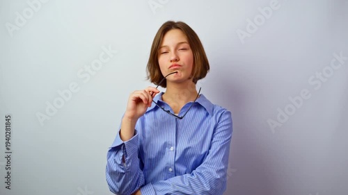 Thoughtful girl holding glasses for vision in thought pensive young woman with eyeglasses considering purchase decision contemplation choosing frames studio portrait