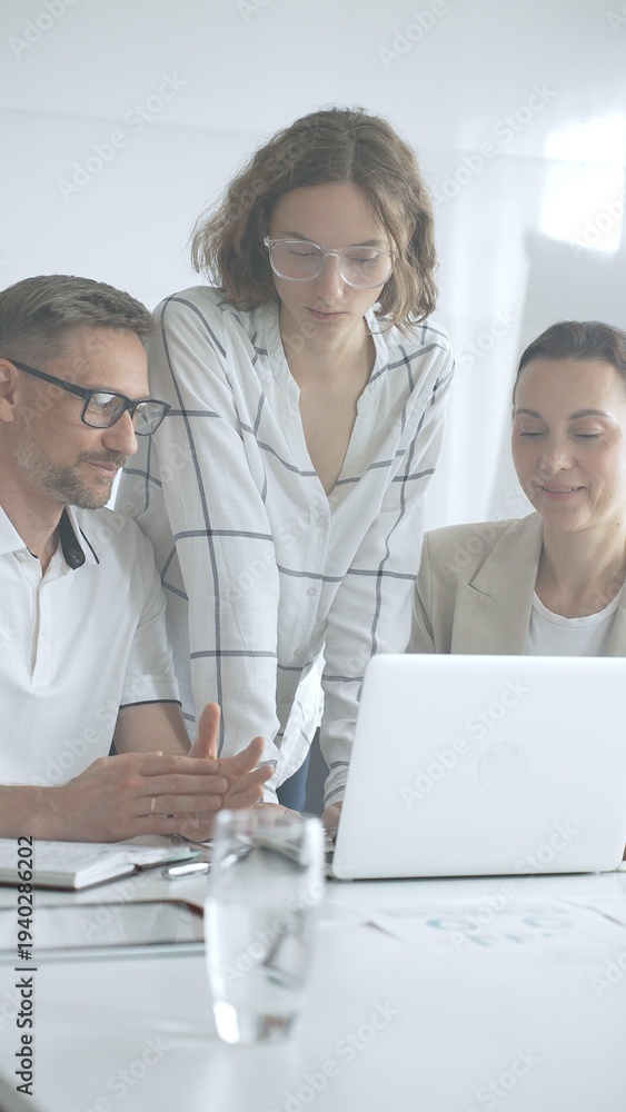 Fototapeta premium Business people team collaborating on a project, analyzing data on a laptop during a productive office meeting, fostering teamwork and strategic planning