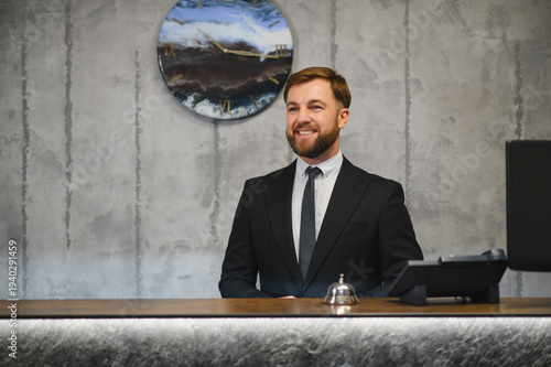 Smiling concierge welcoming guests at hotel reception desk