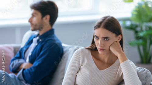 Tableau sur toile A man and a woman sit in a well-lit room with furniture and plants