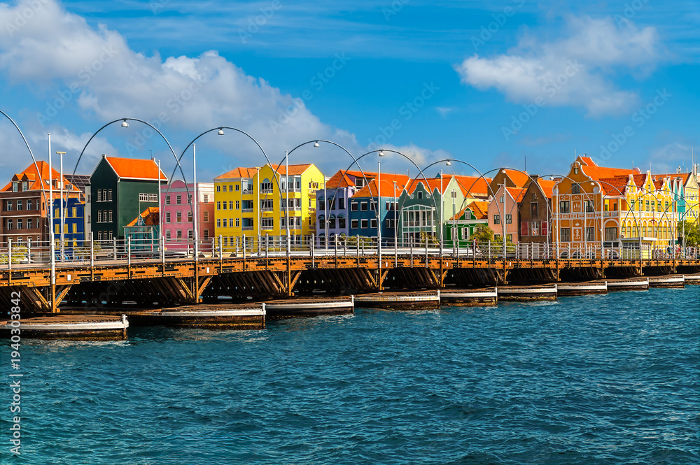 Obraz premium A view across the Queen Emma Bridge towards Handelskade in the Punda District in Willemstad, Curacao on a bright morning