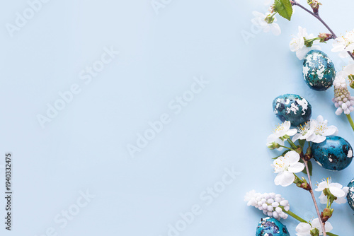 Easter flat lay. Stylish easter eggs and cherry flowers on blue background. Easter celebration, season greetings mockup. Spring modern floral banner