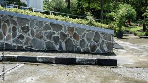 Принти на полотні A decorative stone masonry retaining wall bordering a paved walkway and garden