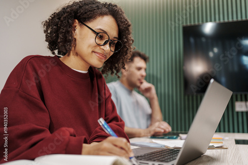 Woman Studying With Pen And Glasses. Young Lady Engaged In Study With Laptop And Attentive Expression
