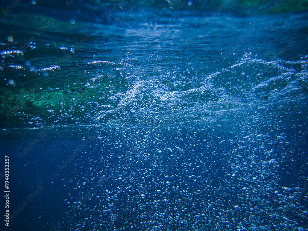 Naklejka premium Underwater background with water bubbles and undersea light rays shine. Dark blue ocean surface seen from underwater. Sunbeams and Sea deep or ocean underwater a Abstract background. sunlight Nature.