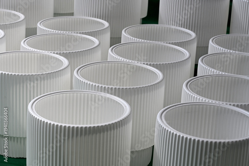 A group of modern, white, fluted cylindrical plant pots arranged on a green surface. Perfect for interior design, gardening, home decor, and retail display concepts.