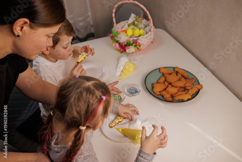 Children decorating homemade Easter cookies with icing and sugar sprinkles. Fun family baking activity for Easter celebration.